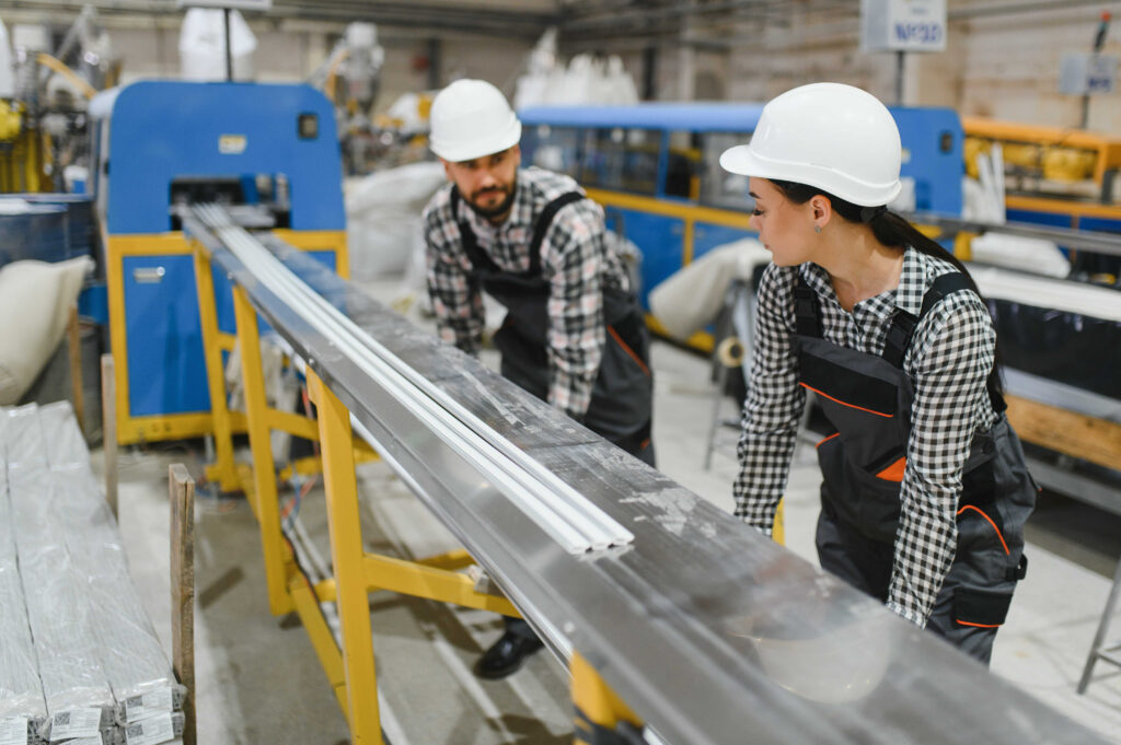two people lifting metal sheets.